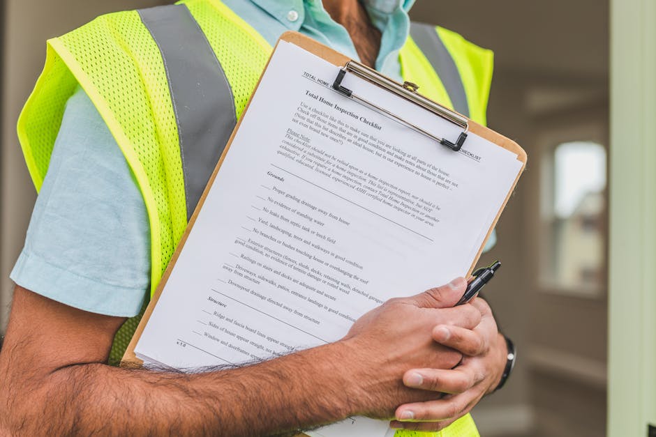 A person wearing a high-visibility yellow vest and a light blue shirt is holding a clipboard with a detailed end of tenancy cleaning checklist for landlords in Hounslow. The checklist includes various cleaning tasks written in black text, and the individual is grasping a black pen. The background features an indoor space with a window and soft lighting, emphasizing a professional approach to surface cleaning, deep cleaning, and sanitisation for residential or commercial properties. The image conveys thorough cleaning inspection, associated with services offered by Carpet Cleaners Hounslow, aimed at ensuring cleanliness and hygiene in preparation for tenancy changes.